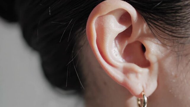 close-up of a Japanese woman's ear wearing a small gold stud earring