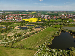 Fototapeta premium Stunning Aerial View of Colorful Vibrant Landscapes Featuring Fields and Water Bodies Koldinger Seen Hannover Pattensen