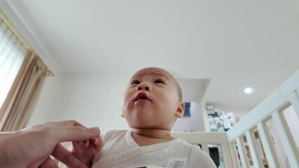An adorable baby gazing upward with curiosity, captured in a well-lit indoor space. The warm atmosphere reflects a moment of wonder and exploration, showcasing the innocence of early childhood.