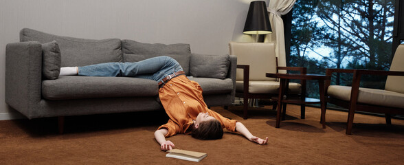 A young woman in casual attire lies exhausted on a sofa, conveying feelings of fatigue and...