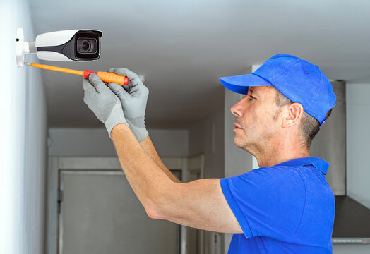 Technician installing security cctv surveillance camera system in smart home.