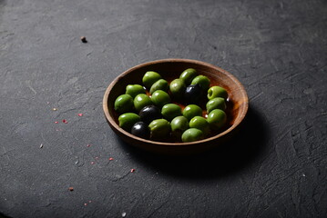 Green olives and black olives in a denim plate on a gray background