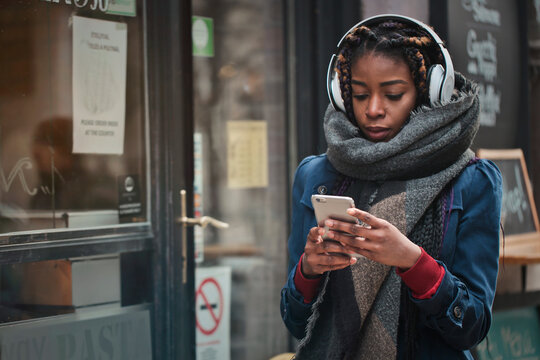 black woman uses a smartphone in the street