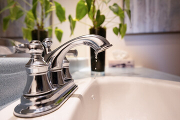 A bathroom faucet slowly dripping water, highlighting a common plumbing issue and water waste