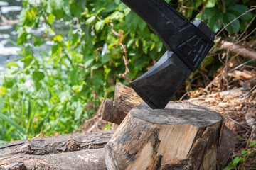 Outdoor scene with an axe embedded in a chopping block beside a pile of logs, suggesting rustic...