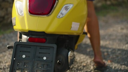 Side Closeup of Barefoot Woman Wearing Flip-Flops Kicking Off Sandal While Sitting on Yellow Scooter, Casual Island Moment Concept