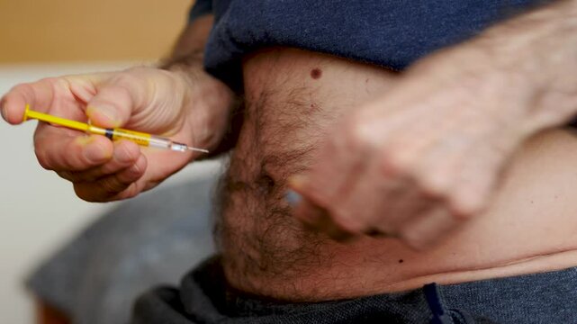 Man is making injection in a belly. Medical injection.
