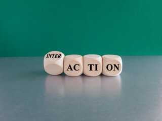 Action and interaction symbol. Turned a cube and changes the word action to interaction. Beautiful green background, grey table. Business and action to interaction concept.