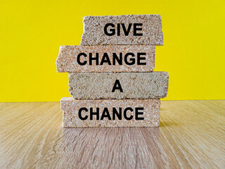 Brick blocks with words Give change a chance on beautiful yellow background, wooden table. Business...