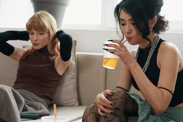 young adult woman drinking orange juice while coworker socializes in modern workplace setting...