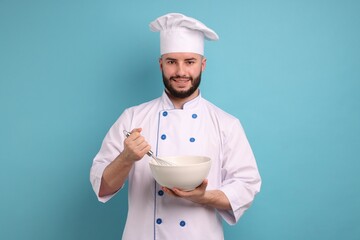 Happy confectioner in uniform holding whisk and bowl on light blue background