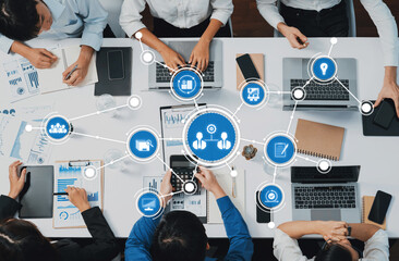 A dynamic team collaborates in a modern workspace, utilizing laptops and digital tools for data...