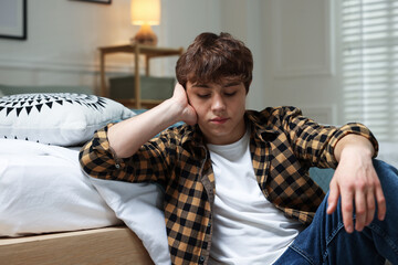 Teen problems. Upset teenage boy on floor at home