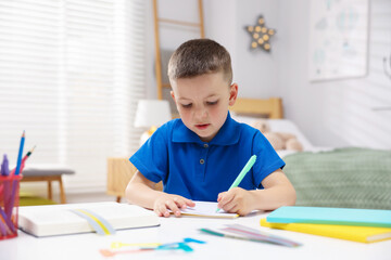 Dyslexia. Little boy writing at table indoors