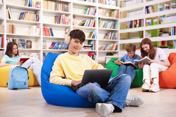 Student with laptop studying on bean bag in library