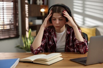Stressed teenage girl studying at desk indoors