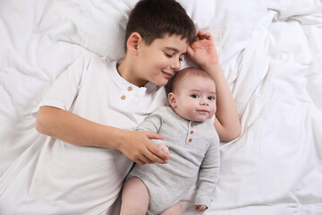 Cute little brothers on bed, top view