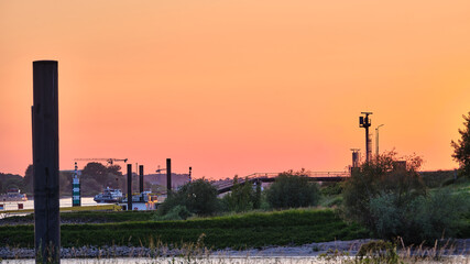 Obraz premium Sunset river landscape with cargo ships and lighthouse near Tolkamer