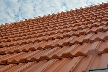 Newly covered roof. New roof covering with red clay tiles. Industrially manufactured tiles on the...