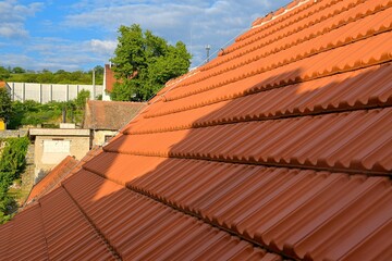 Newly covered roof. New roof covering with red clay tiles. Industrially manufactured tiles on the new roof. Concept of construction, building work, and renovation of the house
