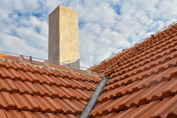 Newly covered roof. New roof covering with burnt red tiles and a chimney on the roof. Industrially manufactured tiles on the new roof. Concept of construction, building work, and renovation  of the ho