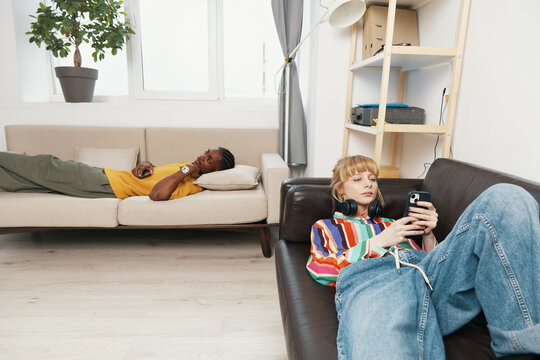 Young adult woman and man relaxing in a bright workplace, socializing as coworkers and friends, representing Gen Z business and working environment with casual style.
