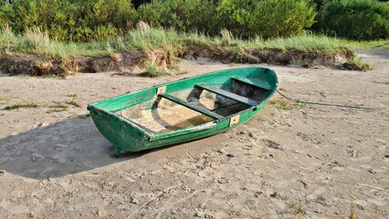 Small old green wooden pleasure boat on yellow sand in the Dunes in spring