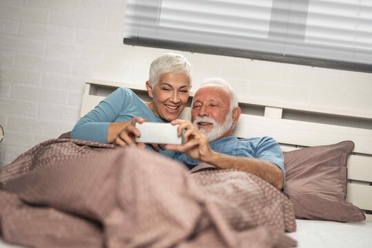 Senior couple lying in bed together using a digital tablet