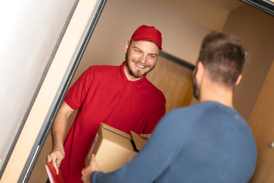 Man checking delivery with cheerful courier at front door