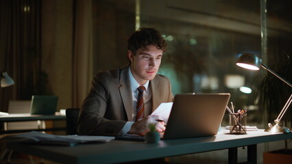 Obraz na płótnie Canvas Night accountant reviewing documents making coffee sip at dark office closeup