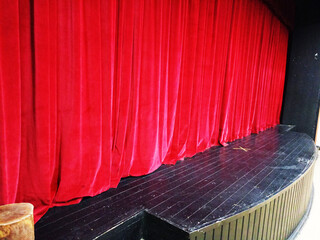 Dark empty cinema, theater stage with red curtains viewed from behind over rows of empty seats