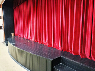 Dark empty cinema, theater stage with red curtains viewed from behind over rows of empty seats