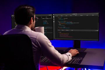 Smart IT developer drinking coffee cup while working in software development coding on pc screen at...