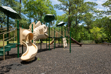 Playground structure with slides in a sunny park surrounded by trees during the afternoon