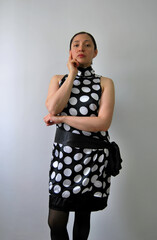beautiful young latina woman in retro polka dot dress with serious expression looking at camera