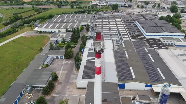 Smoking chimney of modern furniture factory with solar panels in Trnava, Slovakia