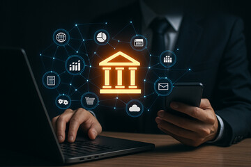 Man using laptop and phone with digital banking icons overlayed in a dark business setting online