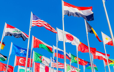 World summit countries national flags waving together on the wind, with American, Japanese, Omani, Chinese, Russian, Iraqi, Egyptian, Somalian, Turkey, Algerian banners waving in the foreground, Doha