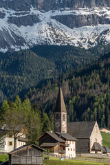 Santa Maddalena church and village in front of dramatic Geisler mountain peaks in the Dolomites, South Tyrol, Italy.