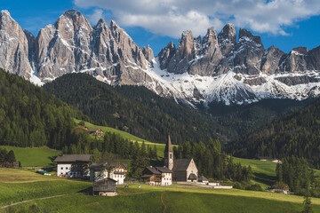 Santa Maddalena church and village in front of dramatic Geisler mountain peaks in the Dolomites, South Tyrol, Italy.