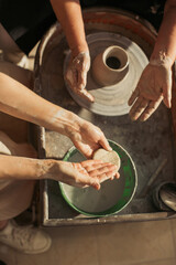Potter showing apprentice how to prepare clay for throwing on pottery wheel