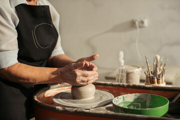 Senior potter creating clay vessel on pottery wheel