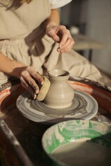 Potter creating clay vase on pottery wheel in workshop
