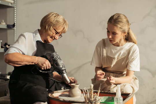 Senior woman using heat gun in pottery class with teacher