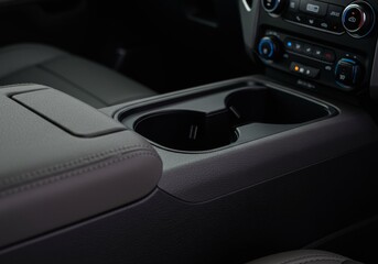 Interior view of a car's center console featuring an armrest and dual cup holders, highlighting comfortable and functional design.