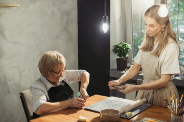 Senior woman learning pottery with teacher in workshop