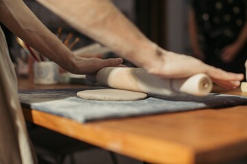 Potter rolling clay with rolling pin in workshop