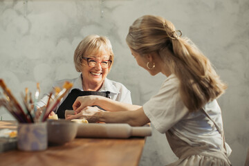 Senior woman learning pottery with teacher in workshop