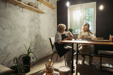 Senior woman and young apprentice creating pottery together in workshop