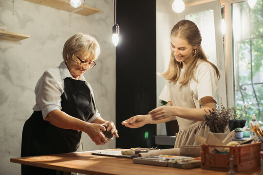 Senior woman learning pottery with young instructor in workshop